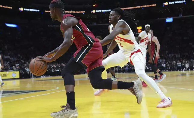 Miami Heat forward Jimmy Butler, left, drives to the basket as Toronto Raptors forward Jonathan Mogbo, right, defends during the first half of an Emirates NBA Cup basketball game, Friday, Nov. 29, 2024, in Miami. (AP Photo/Lynne Sladky)