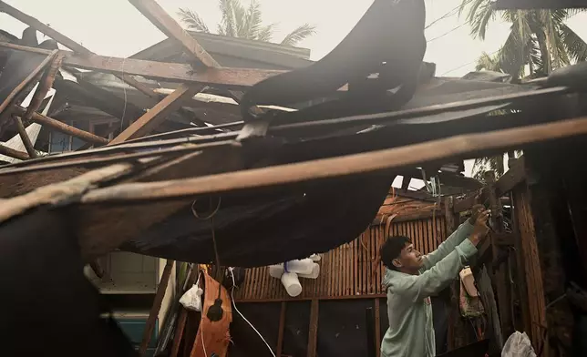 A resident checks belongings from his damaged home that was blown off by strong winds caused by Typhoon Man-yi in the municipality of Baler, Aurora province, northeastern Philippines Monday, Nov. 18, 2024. (AP Photo/Noel Celis)