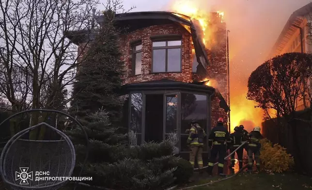 In this photo provided by the Ukrainian Emergency Services on Nov. 21, 2024, rescue workers put out a fire of a burning house damaged by a Russian strike on Dnipro, Ukraine. (Ukrainian Emergency Service via AP)