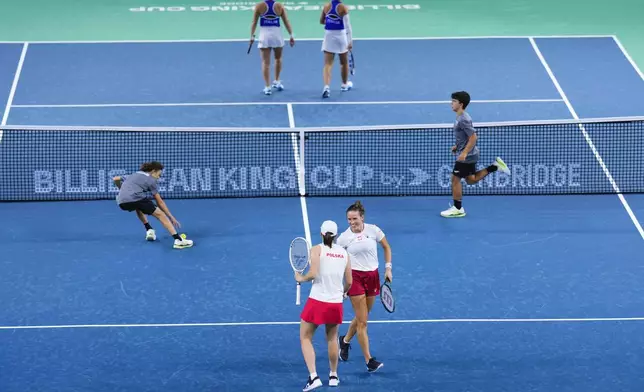 Poland's Katarzyna Kawa and Iga Swiatek, foreground, compete against Italy's Sara Errani and Jasmine Paolini during the Billie Jean King Cup semi-final at Martin Carpena Sports Hall in Malaga, southern Spain, on Monday, Nov. 18, 2024. (AP Photo/Manu Fernandez)