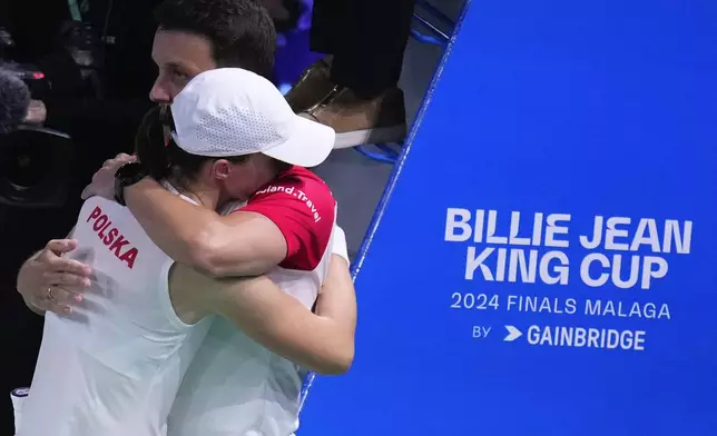 Poland's Iga Swiatek, left, is congratulated by her team's captain Dawid Celt after winning against Italy's Jasmine Paolini during the Billie Jean King Cup semi-final at Martin Carpena Sports Hall in Malaga, southern Spain, on Monday, Nov. 18, 2024. (AP Photo/Manu Fernandez)