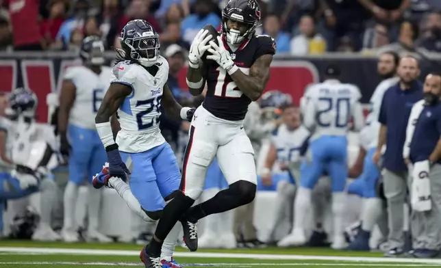 Houston Texans wide receiver Nico Collins (12) makes a catch past Tennessee Titans cornerback Jarvis Brownlee Jr., left, during the first half of an NFL football game Sunday, Nov. 24, 2024, in Houston. (AP Photo/Ashley Landis)