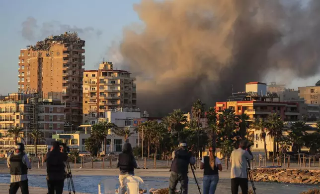 Journalists film as smoke rises from a building hit in Israeli airstrikes in Tyre, southern Lebanon, Saturday, Nov. 16, 2024. (AP Photo/Mohammed Zaatari)