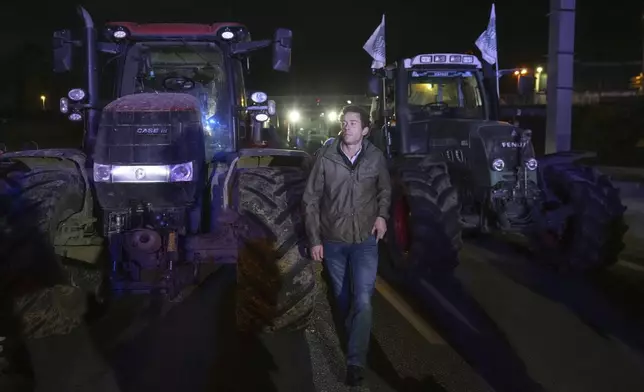 A farmers walks between tractors on a blocked highway in Velizy-Villacoublay, outside Paris, Sunday, Nov. 17, 2024. (AP Photo/Michel Euler)