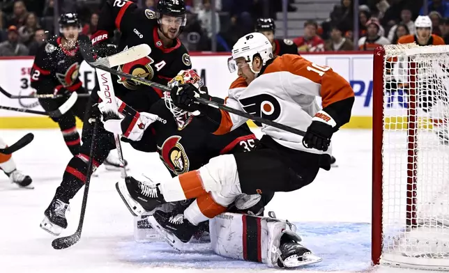 Philadelphia Flyers right wing Bobby Brink (10) falls over Ottawa Senators goaltender Linus Ullmark (35) during third-period NHL hockey game action in Ottawa, Ontario, Thursday, Nov. 14, 2024. (Justin Tang/The Canadian Press via AP)