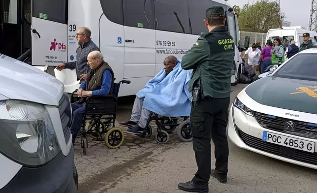 Residents are moved out of the nursing home where least 10 people have died in a fire in Zaragoza, Spain, Friday, Nov. 15, 2024. (AP Photo/Ferran Mallol)