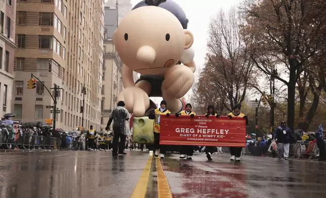 Handlers pull the Diary of a Wimpy Kid balloon down Central Park West during the Macy's Thanksgiving Day Parade, Thursday, Nov. 28, 2024, in New York. (AP Photo/Yuki Iwamura)