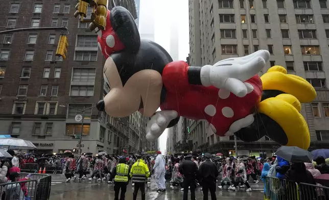 Handlers guide Disney's Minnie Mouse balloon down Sixth Avenue during the Macy's Thanksgiving Day Parade, Thursday, Nov. 28, 2024, in New York. (AP Photo/Julia Demaree Nikhinson)