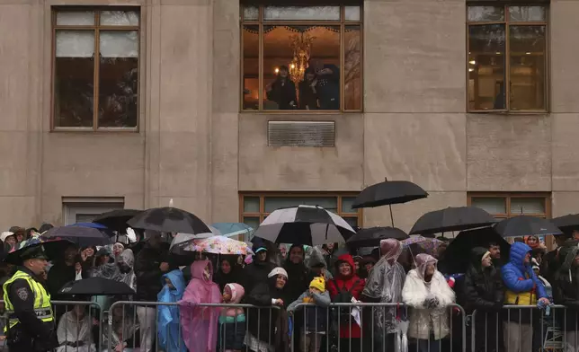 Spectators watch in the rain as the Macy's Thanksgiving Day Parade travels down Central Park West, Thursday, Nov. 28, 2024, in New York. (AP Photo/Yuki Iwamura)