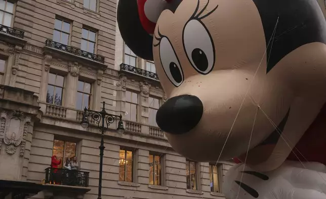 Spectators watch from an apartment balcony as Disney's Minnie Mouse balloon floats by on Central Park West during the Macy's Thanksgiving Day Parade, Thursday, Nov. 28, 2024, in New York. (AP Photo/Yuki Iwamura)