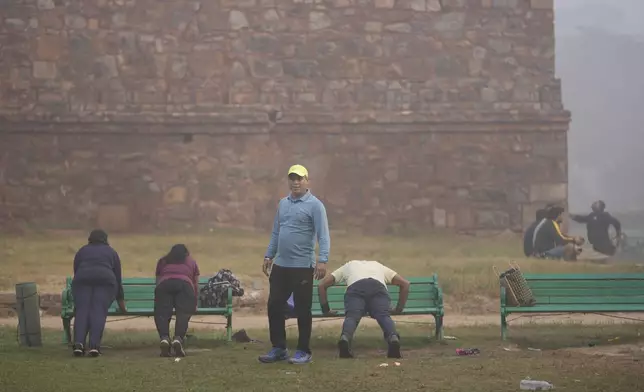 Yoga teacher Ajay Chowdhary, 51, stands beside his students, surrounded by smog in Lodhi Garden in New Delhi, India, Friday, Nov. 15, 2024. (AP Photo/Manish Swarup)