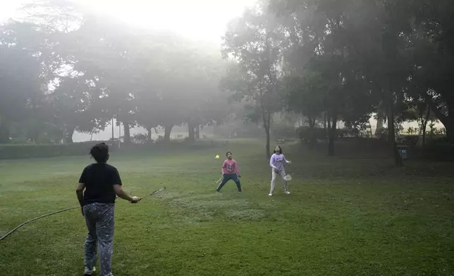 Anita Gahtori plays badminton with her children Sakshi, right, and Devansh in the smog-enveloped Lodhi Gardens in New Delhi, India, Friday, Nov. 15, 2024. (AP Photo/Manish Swarup)