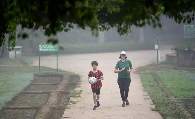 Charu Shankar jogs with her son Agastya Shankar Laul in Lodhi Gardens on a smoggy morning in New Delhi, India, Friday, Nov. 15, 2024. (AP Photo/Manish Swarup)