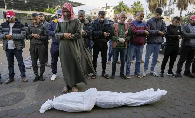 Men pray over the body before the funeral of a victim of an overnight Israeli strike, outside the hospital in Deir al-Balah, Gaza Strip, Sunday Nov. 24, 2024. (AP Photo/Abdel Kareem Hana)