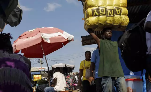 A head porter carries a bale of Second-hand clothes at Kantamanto market, one of the world's largest second-hand clothes markets in Accra, Ghana, Thursday, Oct. 31, 2024. (AP Photo/Misper Apawu)