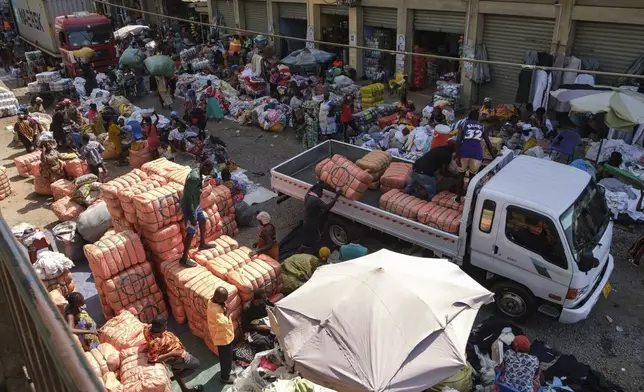 People offload bales of Second-hand clothes from a truck at Kantamanto market, one of the world's largest second-hand clothes markets in Accra, Ghana, Thursday, Oct. 31, 2024. (AP Photo/Misper Apawu)