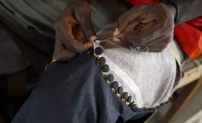 An upcycle designer stitches buttons on an upcycled cloth in the remanufacturing space at the OR Foundation in Accra, Ghana, Thursday, Oct. 24, 2024. (AP Photo/Misper Apawu)