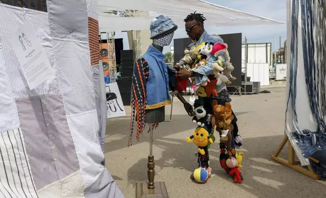 A designer sets up his upcycle outfit on a mannequin during a thrift and an upcycle show in Accra, Ghana, Sunday, Oct. 27, 2024. (AP Photo/Misper Apawu)