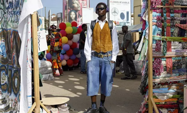 A young man dressed in a thrift outfit poses for a photograph during a thrift and an upcycle show in Accra, Ghana, Sunday, Oct. 27, 2024. (AP Photo/Misper Apawu)