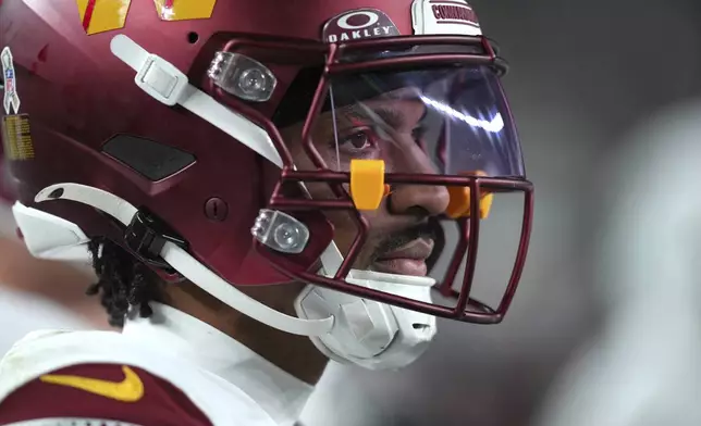 Washington Commanders quarterback Jayden Daniels watches from the sideline during the second half of an NFL football game against the Philadelphia Eagles Thursday, Nov. 14, 2024, in Philadelphia. (AP Photo/Chris Szagola)