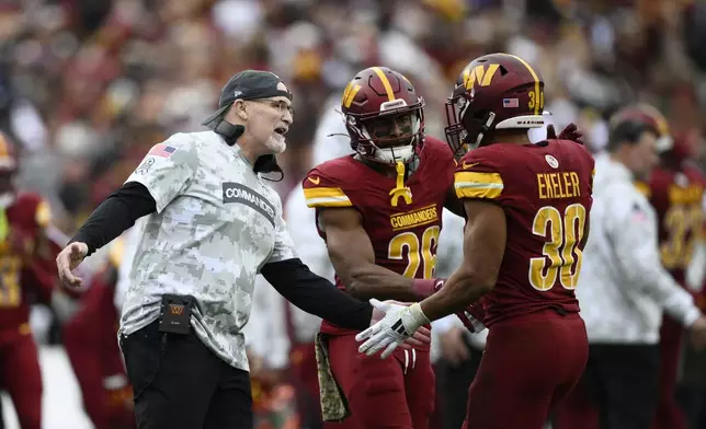 Washington Commanders head coach Dan Quinn reaches out to running back Austin Ekeler (30) after his touchdown during the first half of an NFL football game against the Pittsburgh Steelers, Sunday, Nov. 10, 2024, in Landover, Md. (AP Photo/Nick Wass)