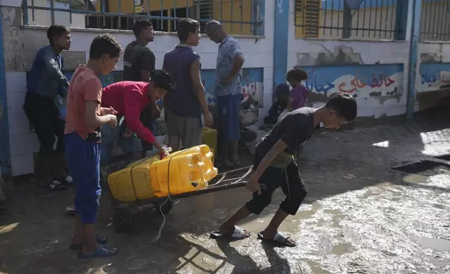 Palestinians collect clean drinking water at a desalination plant that now operates round the clock in Deir al-Balah, Gaza, a resource they barely had any access to during the war, Thursday, Nov. 14, 2024. (AP Photo/Abdel Kareem Hana)