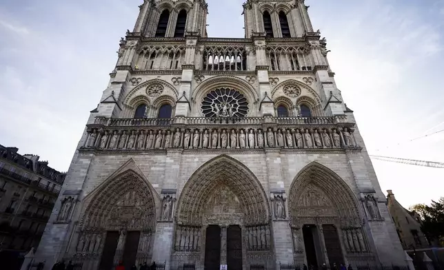 People stand outside Notre-Dame Cathedral in Paris, Friday Nov. 29 2024 before French President Emmanuel Macron's final visit to the construction site to see the restored interiors before the iconic monument's reopening for worship on Dec. 8. (Sarah Meyssonnier, Pool via AP)