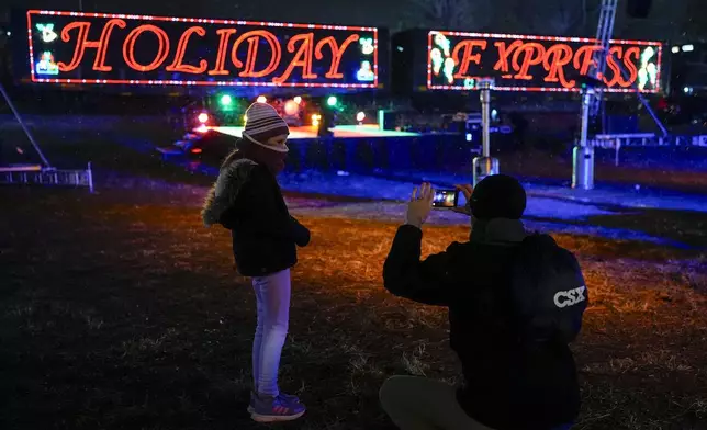 Eden Jordan, left, poses for her father Tim Jordan, right, in front of the CSX Holiday Express, Thursday, Nov. 21, 2024, in Erwin, Tenn. The railway company held a celebration and concert for the town affected by Hurricane Helene. (AP Photo/George Walker IV)