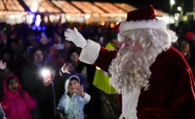 Santa Claus waves to children during a visit of the CSX Holiday Express, Thursday, Nov. 21, 2024, in Erwin, Tenn. The railway company held a celebration and concert for the town affected by Hurricane Helene. (AP Photo/George Walker IV)