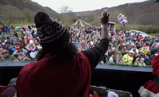 A volunteer tosses toys to people during the 82nd run of the CSX Santa Train, Saturday, Nov. 23, 2024, in Kermit, Va. (AP Photo/George Walker IV)