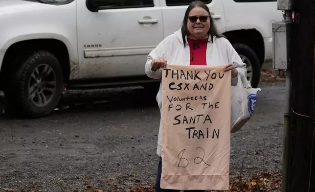 Sandra Owens holds a sign thanking volunteers during the 82nd run of the CSX Santa Train, Saturday, Nov. 23, 2024, in Haysi, Va. (AP Photo/George Walker IV)