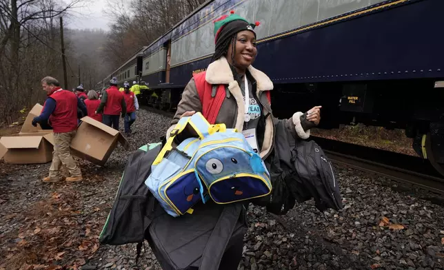 Ilizabeth White delivers gift bags to children during the 82nd run of the CSX Santa Train, Saturday, Nov. 23, 2024, in Fremont, Va. The train brings presents to small towns along a 110-mile portion of the railroad line in rural Appalachian Tennessee, Kentucky and Virginia. (AP Photo/George Walker IV)