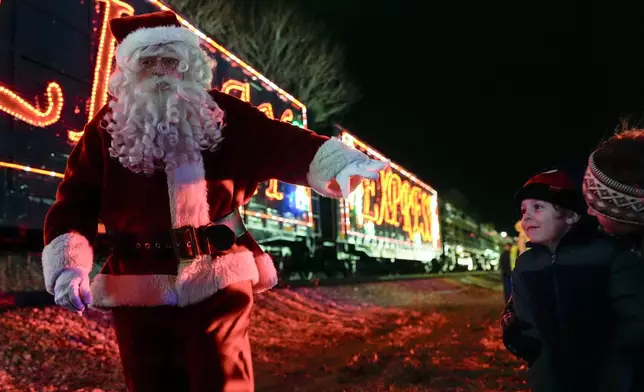 Santa Claus waves to children during a visit of the CSX Holiday Express Thursday, Nov. 21, 2024, in Erwin, Tenn. The railway company held a celebration and concert for the town affected by Hurricane Helene. (AP Photo/George Walker IV)