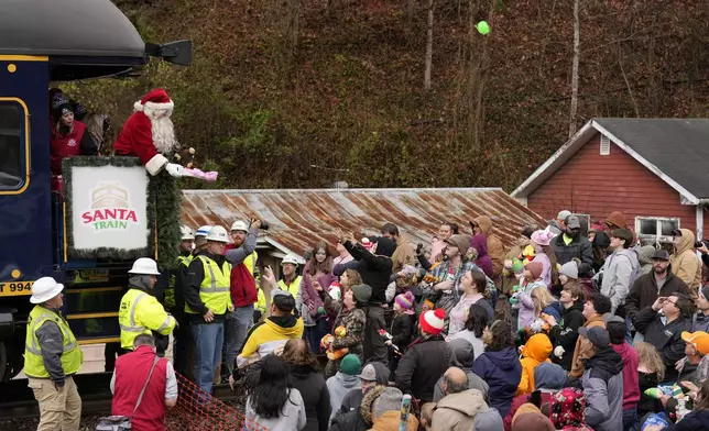 Santa Claus tosses toys to people during the 82nd run of the CSX Santa Train, Saturday, Nov. 23, 2024, in Dante, Va. (AP Photo/George Walker IV)