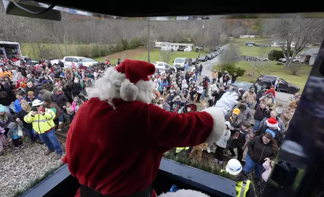 Santa Claus waves to people during the 82nd run of the CSX Santa Train, Saturday, Nov. 23, 2024, in Kermit, Va. The train brings presents to small towns along a 110-mile portion of the railroad line in rural Appalachian Tennessee, Kentucky and Virginia. (AP Photo/George Walker IV)