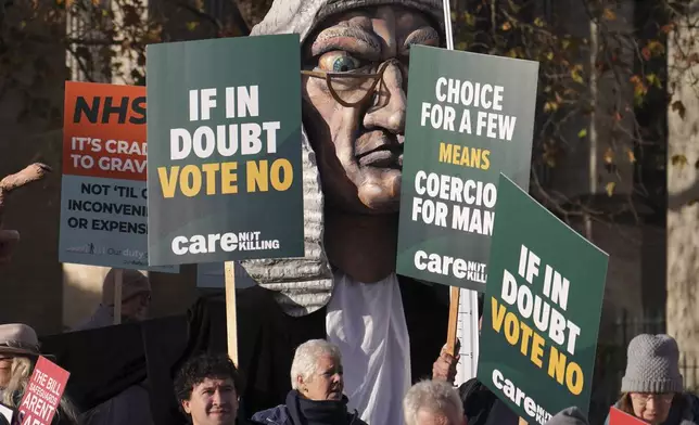 Protesters show placards in front of Parliament in London, Friday, Nov. 29, 2024 as British lawmakers started a historic debate on a proposed to help terminally ill adults end their lives in England and Wales.(AP Photo/Alberto Pezzali)