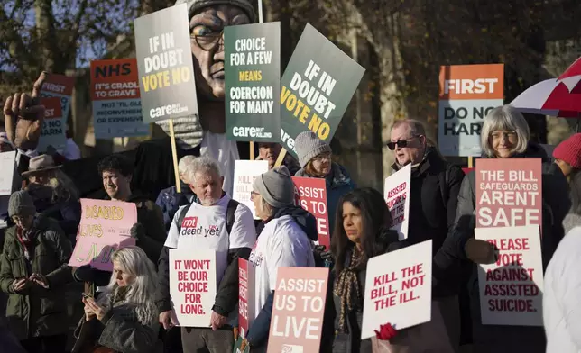 Protesters show placards in front of Parliament in London, Friday, Nov. 29, 2024 as British lawmakers started a historic debate on a proposed to help terminally ill adults end their lives in England and Wales.(AP Photo/Alberto Pezzali)