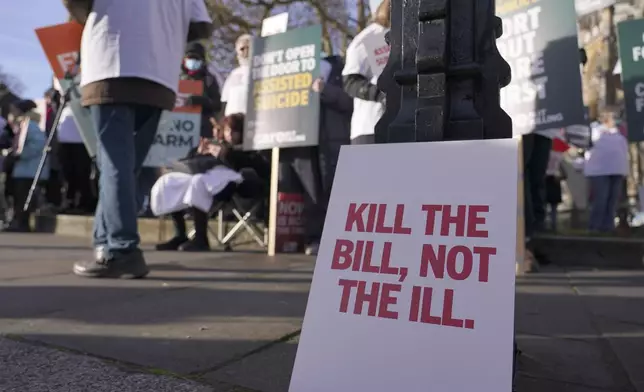 A poster leans on a lambpost as protesters demonstrate in front of Parliament in London, Friday, Nov. 29, 2024 as British lawmakers started a historic debate on a proposed to help terminally ill adults end their lives in England and Wales.(AP Photo/Alberto Pezzali)