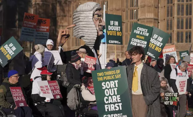 Protesters show posters and placards in front of Parliament in London, Friday, Nov. 29, 2024 as British lawmakers started a historic debate on a proposed to help terminally ill adults end their lives in England and Wales.(AP Photo/Alberto Pezzali)