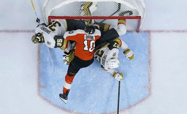 Philadelphia Flyers' Bobby Brink, center, collides with Vegas Golden Knights' Shea Theodore, right, and Ilya Samsonov during overtime in an NHL hockey game, Monday, Nov. 25, 2024, in Philadelphia. (AP Photo/Matt Slocum)