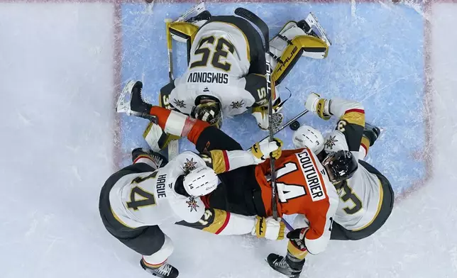 Philadelphia Flyers' Sean Couturier, center, collides with Vegas Golden Knights' Brayden McNabb, right, Nicolas Hague, left, and Ilya Samsonov during overtime in an NHL hockey game, Monday, Nov. 25, 2024, in Philadelphia. (AP Photo/Matt Slocum)