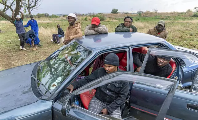 Relatives of miners and community members wait at a mine shaft where illegal miners are trapped in a disused mine in Stilfontein, South Africa, Thursday, Nov. 14, 2024. (AP Photo/Jerome Delay)