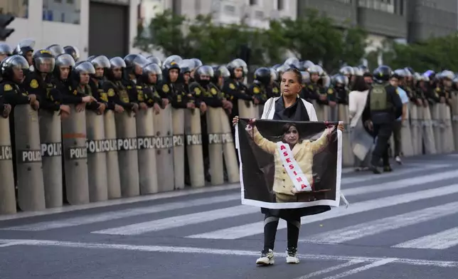 An anti-government protester holds a photo of Peru's President Dina Boluarte with a sash that reads in Spanish, "Assassin" during a demonstration on the sidelines of the Asia-Pacific Economic Cooperation (APEC) summit in Lima, Peru, Wednesday, Nov. 13, 2024. (AP Photo/Fernando Vergara)