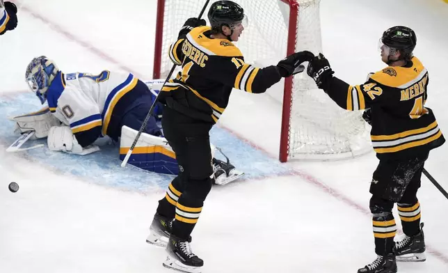 Boston Bruins' Trent Frederic (11) celebrates his first goal of the first period against St. Louis Blues' Jordan Binnington (50) with teammate Georgii Merkulov (42) during an NHL hockey game, Saturday, Nov. 16, 2024, in Boston. (AP Photo/Michael Dwyer)