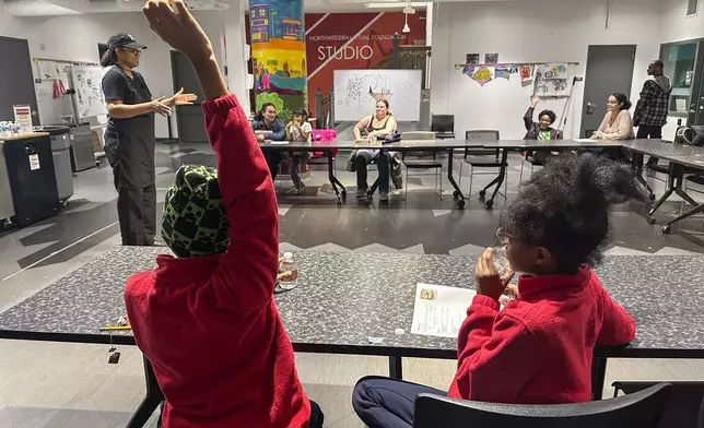 A child raises his hand to answer a question asked by Chef Sharrie Agee at the Milwaukee Public Library’s Snack Hack program for kids on Nov. 19, 2024, Milwaukee. (AP Photo/Devi Shastri)