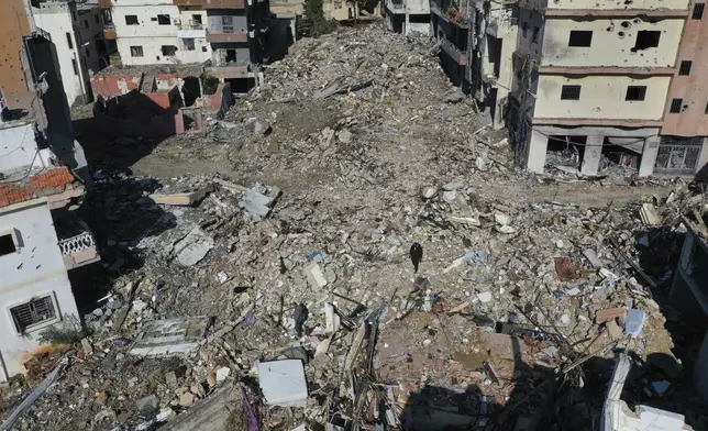 Residents walk on the rubble of destroyed buildings after they returned to Qana village, southern Lebanon, Thursday, Nov. 28, 2024 following a ceasefire between Israel and Hezbollah that went into effect on Wednesday.(AP Photo/Hussein Malla)