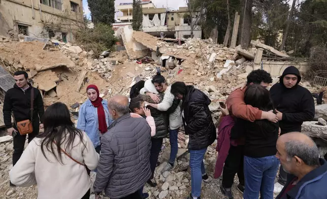 Displaced residents hug as they stand in front of the rubble of their destroyed house in Baalbek, eastern Lebanon, Thursday, Nov. 28, 2024. (AP Photo/Hassan Ammar)