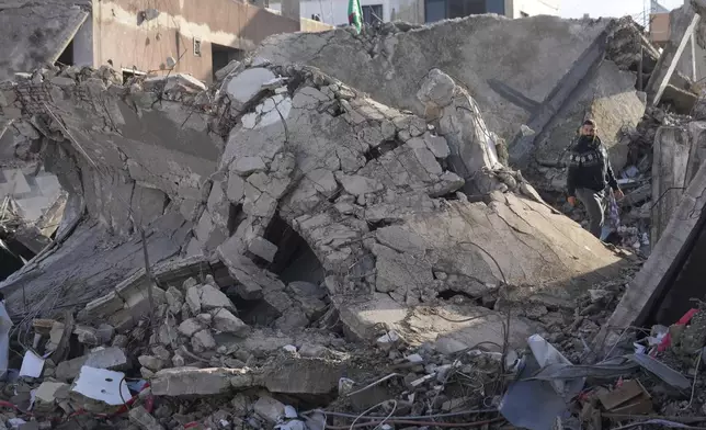 A man stands on the rubble of a destroyed building that housed his apartment in Tyre, southern Lebanon, Thursday, Nov. 28, 2024. (AP Photo/Hussein Malla)