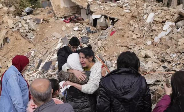 Displaced residents hug as they stand in front of the rubble of their destroyed house in Baalbek, eastern Lebanon, Thursday, Nov. 28, 2024. (AP Photo/Hassan Ammar)