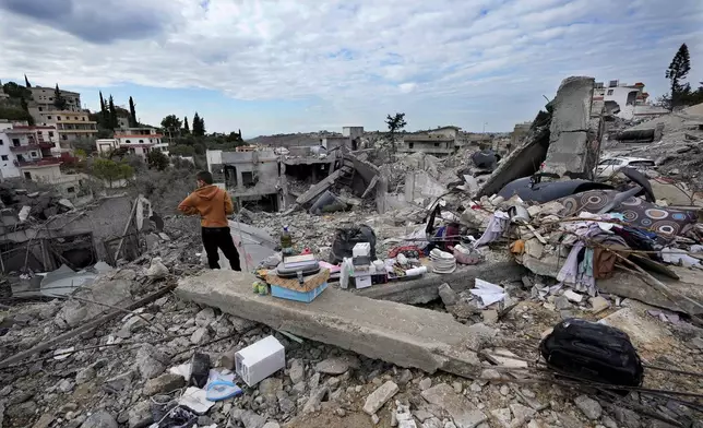 A person stands next to remains and his family destroyed house after he returned to Chehabiyeh village, southern Lebanon, Thursday, Nov. 28, 2024 following a ceasefire between Israel and Hezbollah that went into effect on Wednesday. (AP Photo/Hussein Malla)